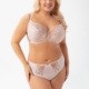 Une femme souriante portant le Soutien gorge Evia noir pose sur un fond blanc uni. Mode Grande taille