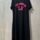 Robe sweat noire avec inscription rose "Los Angeles", accrochée sur un cintre mural. Mode Grande taille