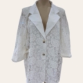 Le Blazer en dentelle est un blazer en dentelle blanche transparente avec un motif cachemire, de larges revers et deux boutons dorés, présenté sur un mannequin. Mode Grande taille