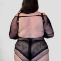 Une personne aux cheveux longs et foncés est vue de dos portant le Body résille dos ouvert avec motif sur un fond uni. Mode Grande taille
