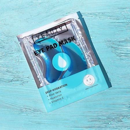 Un emballage de Masque hydratant pour les yeux pour une hydratation en profondeur repose sur une surface texturée de couleur turquoise. Mode Grande taille