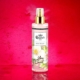 Un flacon pulvérisateur de Brume yani, un doux spray corporel, posé sur un fond rose vif avec des éclaboussures d'eau. Mode Grande taille