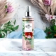 Une bouteille de spray corporel floral Brume Sweet Licorice est posée sur un évier, avec des fleurs et de l'herbe de la pampa en arrière-plan. Mode Grande taille