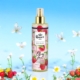 Vaporisateur corporel Brume Oh my love au motif framboise et floral, placé parmi des fleurs, des papillons et un ciel bleu vif. Mode Grande taille