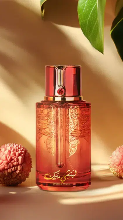 Parfum Musc Lychee : Un flacon rouge avec une écriture arabe dorée, entouré de litchis et de feuilles vertes, se détache sur un fond beige. Mode Grande taille
