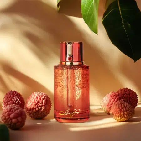 Parfum Musc Lychee : Un flacon rouge avec une écriture arabe dorée, entouré de litchis et de feuilles vertes, se détache sur un fond beige. Mode Grande taille