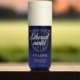 Un flacon de brume de parfum Ethereal Violet V.V. Love sur une surface en bois avec un arrière-plan flou en extérieur. Mode Grande taille
