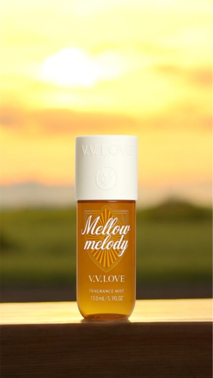 Une bouteille de brume de parfum V.V. Love Mellow Melody sur une surface en bois avec un arrière-plan de coucher de soleil. Mode Grande taille