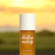 Une bouteille de brume de parfum V.V. Love Mellow Melody sur une surface en bois avec un arrière-plan de coucher de soleil. Mode Grande taille