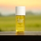 Une bouteille jaune étiquetée "Sweet nectar V.V. LOVE" est posée sur une surface en bois avec un arrière-plan flou de coucher de soleil. Mode Grande taille