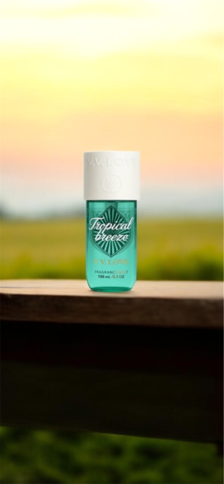 Un flacon de parfum turquoise étiqueté "Fruital Breeze" est posé sur un rebord en bois avec un arrière-plan flou de coucher de soleil. Mode Grande taille