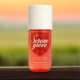 Une bouteille de brume de parfum Serene Grove V.V. Love sur une surface en bois avec un arrière-plan flou de coucher de soleil en extérieur. Mode Grande taille