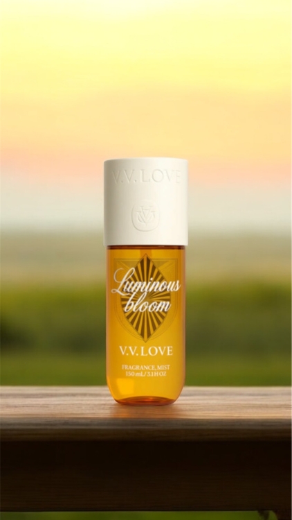 Un flacon de brume parfumée V.V. Love est posé sur une surface en bois avec un arrière-plan flou en extérieur. Mode Grande taille