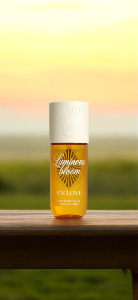 Un flacon de brume parfumée V.V. Love est posé sur une surface en bois avec un arrière-plan flou en extérieur. Mode Grande taille