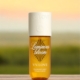 Un flacon de brume parfumée V.V. Love est posé sur une surface en bois avec un arrière-plan flou en extérieur. Mode Grande taille