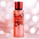 Un flacon de parfum Brume rose avec un bouchon rouge et un motif floral se détache sur un fond rose flou. Mode Grande taille