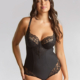 Une femme sourit sur un fond gris neutre. Elle porte le body Body Allure Noir en dentelle noire. Mode Grande taille