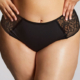Une personne modèle la Culotte Sophia, sous-vêtement noir bordé de dentelle, les mains sur les hanches, montrée de la mi-torse à la partie supérieure des cuisses. Mode Grande taille