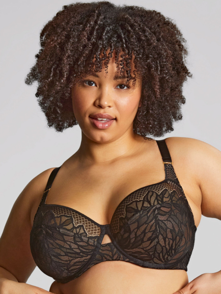 Une femme aux cheveux bouclés porte le soutien-gorge emboîtant Sophia, un soutien-gorge en dentelle noire, et regarde la caméra avec assurance sur un fond uni. Mode Grande taille