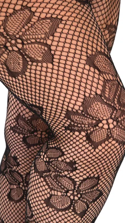 Gros plan sur des jambes portant des Collants Résille Blossom, des bas résille noirs aux motifs floraux audacieux. Mode Grande taille