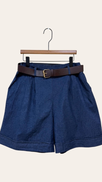 Jupe culotte en denim détail boutons, présentée sur un cintre en bois contre un fond uni. Mode Grande taille