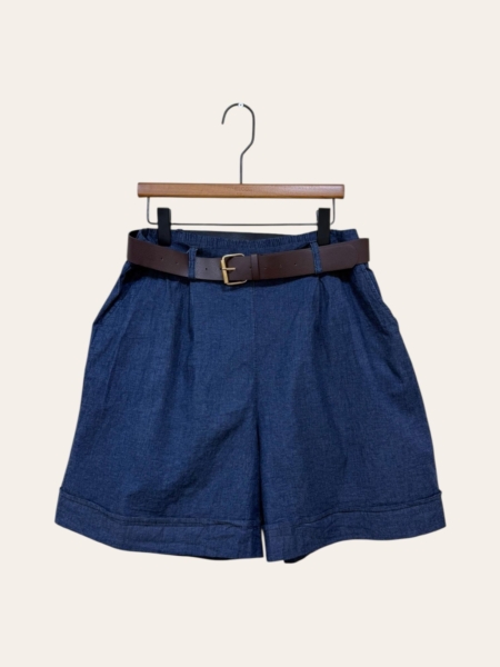 Jupe culotte en denim détail boutons, présentée sur un cintre en bois contre un fond uni. Mode Grande taille