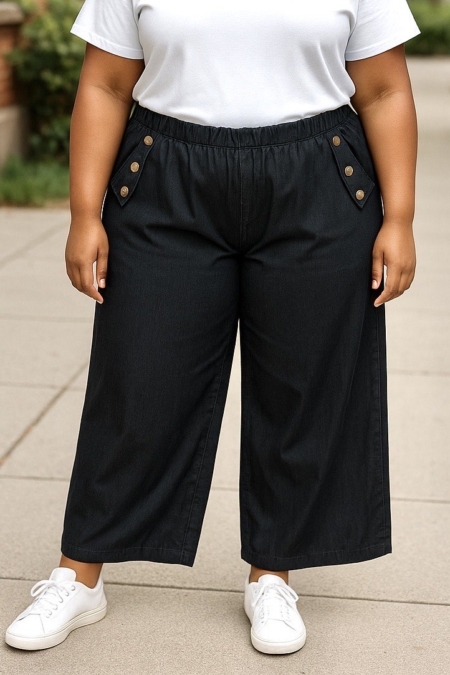 Personne portant le pantalon jambes larges avec boutons décoratifs, un t-shirt blanc et des baskets blanches, debout à l'extérieur. Mode Grande taille