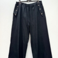 Pantalon jambes larges avec boutons décoratifs, taille élastique, exposé sur un cintre. Mode Grande taille