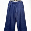 Pantalon jambes larges avec boutons décoratifs, en denim bleu à taille élastique et détails boutons sur les poches, suspendu sur un cintre. Mode Grande taille