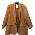 Blazer ouvert de couleur rouille avec deux poches sur le devant, présenté sur un cintre sur fond blanc. Mode Grande taille