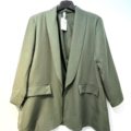 Blazer ouvert en vert olive avec revers, deux poches avant et une étiquette, présenté sur un cintre noir contre un mur blanc. Mode Grande taille