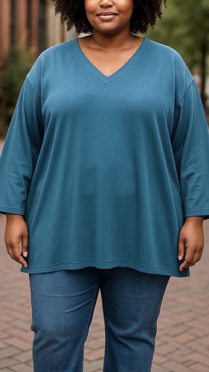 Une personne portant le maillot Tunique sweat col V en et un jean se tient sur un trottoir en briques dans un environnement urbain. Mode Grande taille
