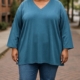 Une personne portant le maillot Tunique sweat col V en et un jean se tient sur un trottoir en briques dans un environnement urbain. Mode Grande taille