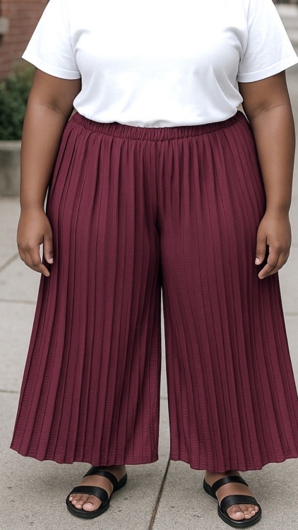 Personne portant un t-shirt blanc, un pantalon jupe culotte plissé de couleur bordeaux et des sandales noires, debout sur un trottoir. Mode Grande taille