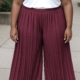 Personne portant un t-shirt blanc, un pantalon jupe culotte plissé de couleur bordeaux et des sandales noires, debout sur un trottoir. Mode Grande taille