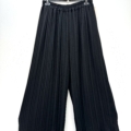 Pantalon jupe culotte plissé en noir avec des jambes larges, des plis et une taille élastique, suspendu sur un cintre noir sur fond blanc. Mode Grande taille