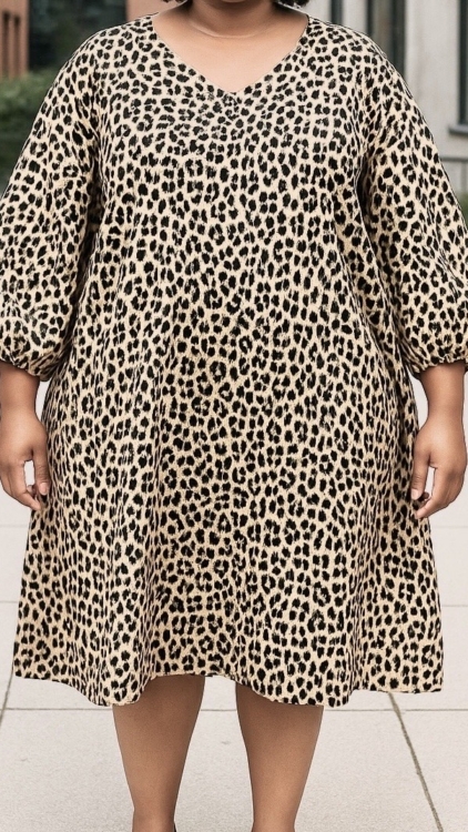 Personne portant la "Robe fluide manches bouffantes imprimé animalier", une robe ample à manches longues imprimée animalier, debout en plein air sur un chemin pavé. Mode Grande taille