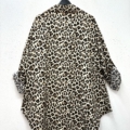 Chemise imprimée animalier à manches longues suspendue sur un cintre noir devant un mur blanc, vue de dos. Mode Grande taille