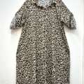 Robe chemise imprimé animalier à manches longues suspendue sur un cintre noir contre un mur blanc. Mode Grande taille
