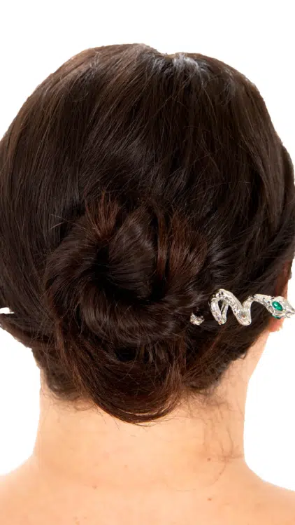 Femme aux cheveux noirs en chignon, ornée de l'Épingle à Cheveux Médusa, une épingle à cheveux en argent en forme de serpent aux yeux verts. Mode Grande taille