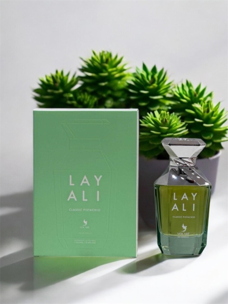 Un flacon et une boîte de parfum Layali Classic Pistachio présentés devant des plantes succulentes vertes. Mode Grande taille