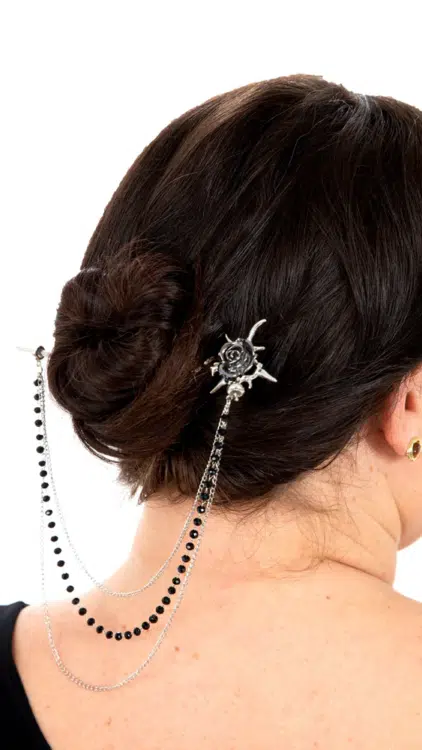 Femme aux cheveux noirs coiffés en chignon, ornés de l'épingle à cheveux épine de rose en argent et de chaînes drapées noires et argentées. Mode Grande taille