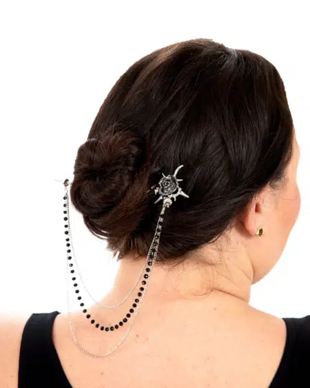 Femme aux cheveux noirs coiffés en chignon, ornés de l'épingle à cheveux épine de rose en argent et de chaînes drapées noires et argentées. Mode Grande taille