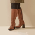Personne portant des Bottes mollets larges 2XL Mélissa - Gabylou, des collants noirs et une jupe verte, debout sur un fond beige. Mode Grande taille