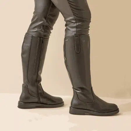 Une personne portant les bottes d'équitation Isabelle XL 6 Gabylou à semelle large en noir se tient sur un fond beige, associées à un pantalon noir. Mode Grande taille