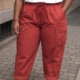 Une personne portant le Pantalon cargo en coton super stretch, un t-shirt blanc et des baskets blanches se tient dans une rue pavée. Mode Grande taille