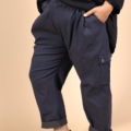 Une personne portant le Pantalon cargo en coton super stretch de couleur marine, un haut noir et des baskets blanches se tient debout, une main dans la poche. Mode Grande taille