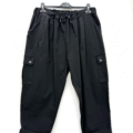 Pantalon cargo en coton super stretch noir avec taille à cordon et bas roulés, suspendu sur un cintre noir devant un fond blanc. Mode Grande taille
