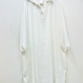 Une "Robe col chemise fendue sur les côtés", ample et longue avec des manches longues, est suspendue à un cintre noir contre un mur blanc. Mode Grande taille