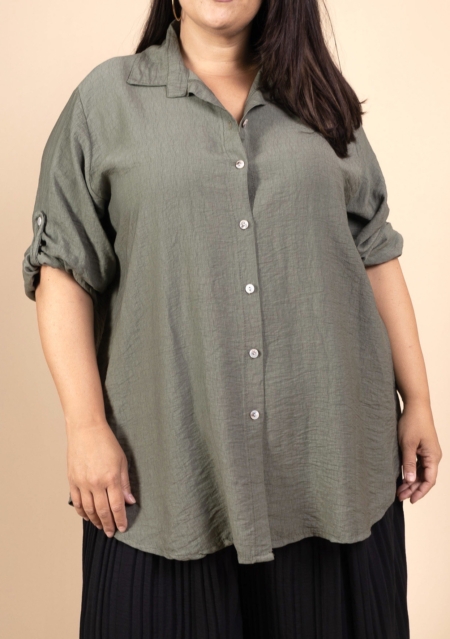 Une personne portant la Chemise en viscose, une chemise à boutons vert olive avec des manches roulées, associée à un pantalon noir. Mode Grande taille